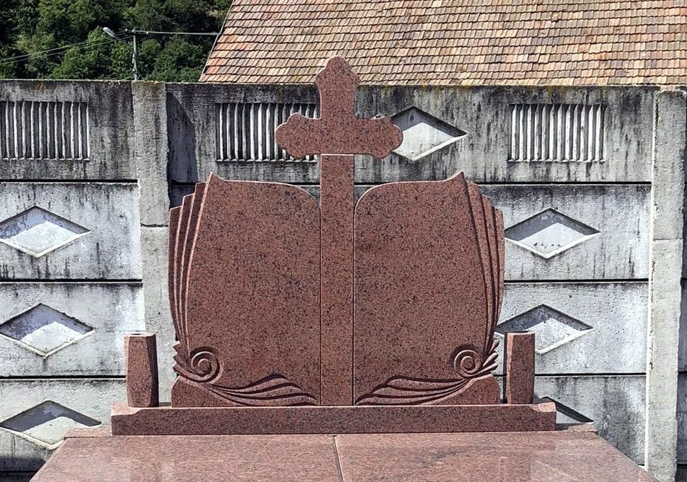 Monument funerar dublu din granit roșu în formă de carte deschisă, cu cruce