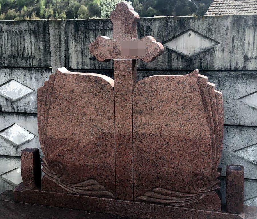 Cruce funerară dublă din granit roșu cu cărți sculptate și cruce centrală, expusă în atelierul Mogut.