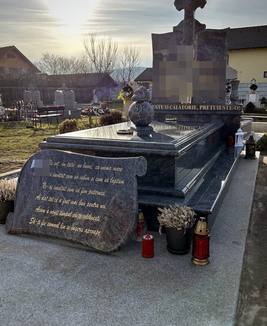 Monument funerar la comandă din granit albastru cu sculptură decorativă și pupitru cu versuri, montat în cimitir.