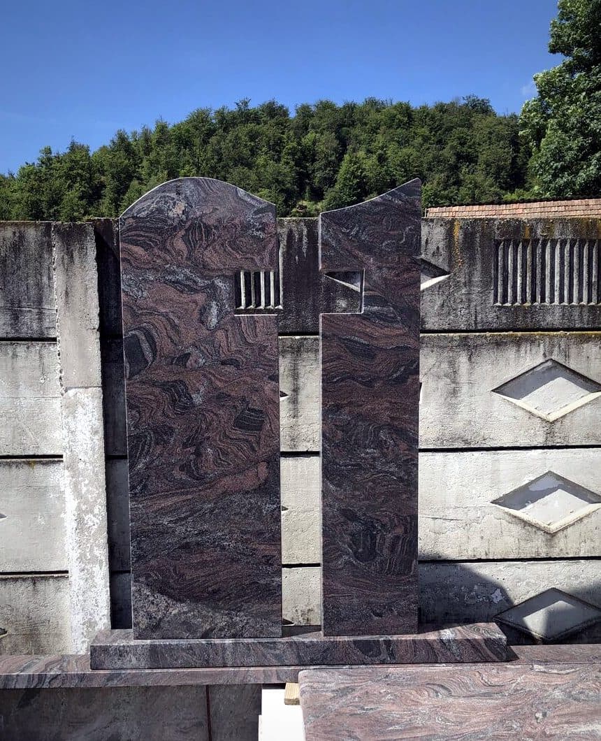 Monument funerar dublu modern din granit roșu cu stele înalte și cruce decupată, în atelierul Mogut.