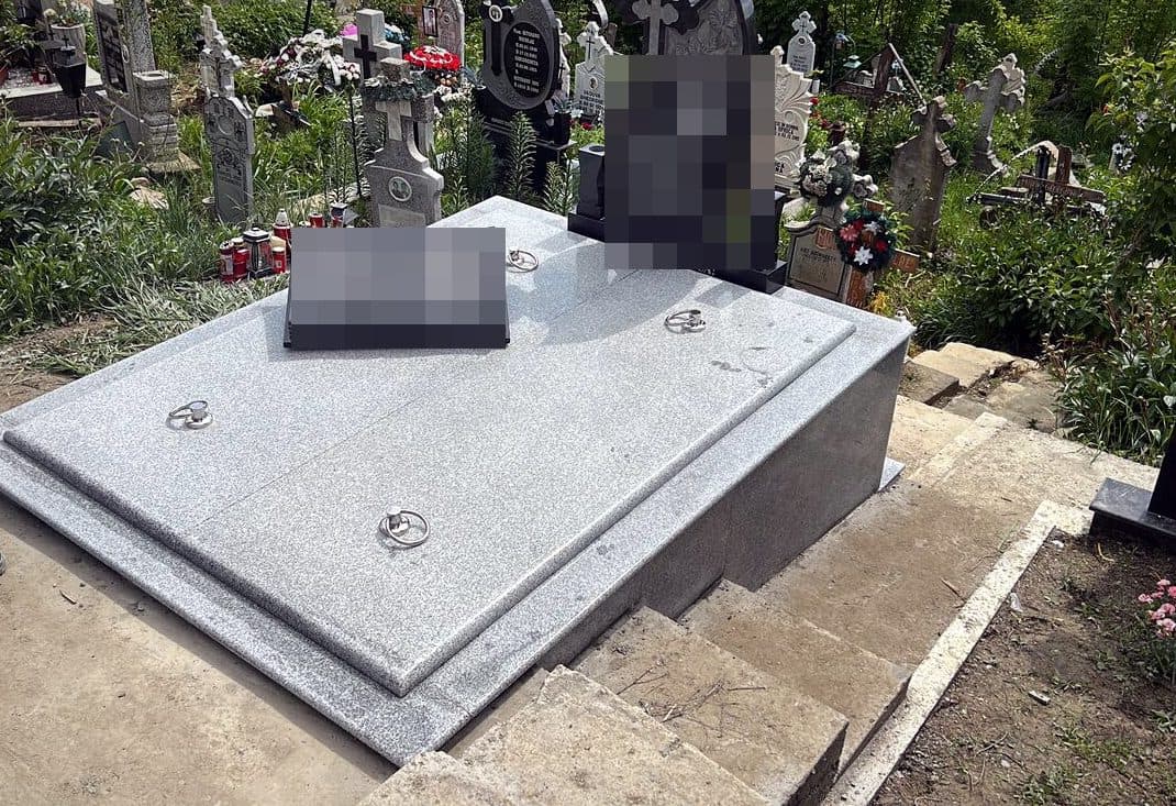 Mormânt clasic din granit gri cu carte deschisă sculptată și monument din granit negru, montat în cimitir.